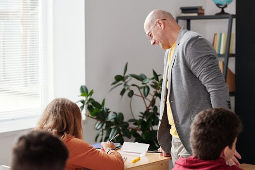 Teacher assisting students in a bright classroom setting.